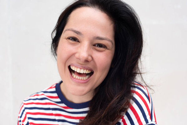 Close up portrait of happy young woman laughing by white background 