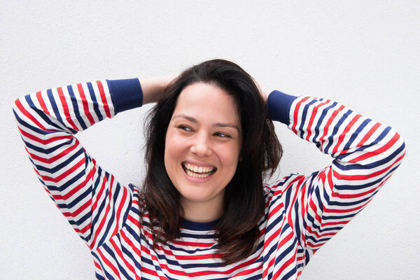Portrait young woman relaxing with hands behind head and smiling by white background 