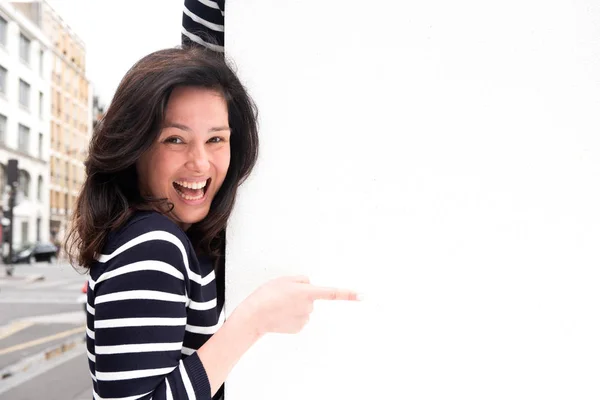 Portrait laughing young woman pointing to white background copy space