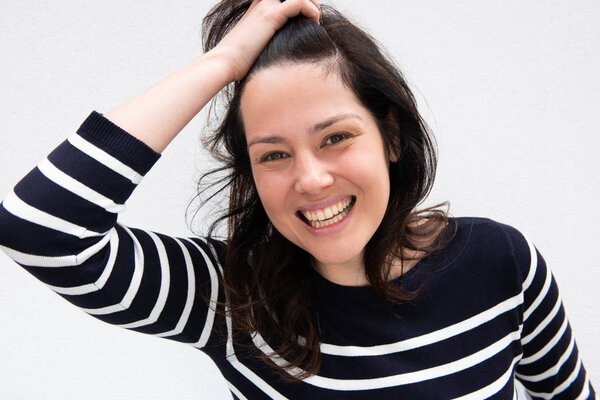 Portrait young woman laughing with hand in hair by white background