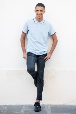 Beyaz duvarda gülümseyen genç bir Kuzey Afrikalı portresi