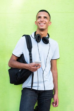 Portre mutlu Kuzey Afrikalı üniversite öğrencisi yeşil arka plana karşı cep telefonuyla 