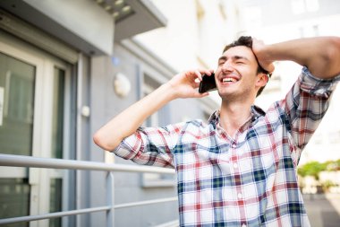 Dışarıda cep telefonuyla konuşan gülümseyen genç adamın portresi. 