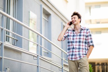 Portre yakışıklı genç adam dışarıda duruyor ve cep telefonuyla konuşuyor.