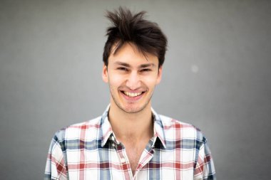 Gri arkaplanlı mutlu genç adamın ön portresini kapat.