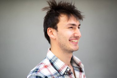 Mutlu genç adamın gri arka plandaki portresini kapat. 
