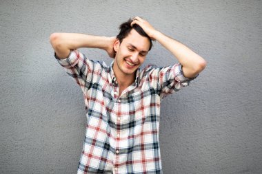 Elleri saçında mutlu genç bir adamın portresi.