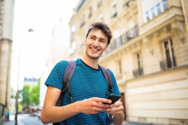 Şehirde cep telefonuyla gülümseyen genç bir adamın portresi.