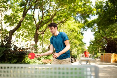 Park 'ta masa tenisi oynayan aktif bir gencin portresi