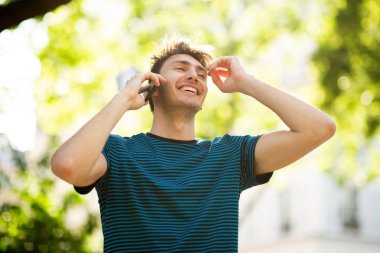 Parkta telefonla konuşan gülümseyen genç adam portresi