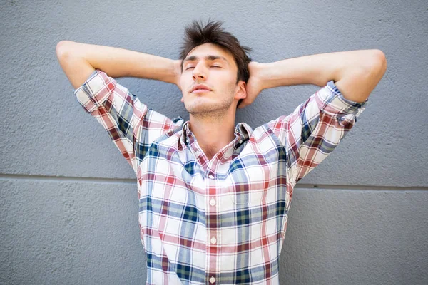 Portrait Young Man Leaning Gray Wall Hands Head Eyes Closed — Stock Photo, Image
