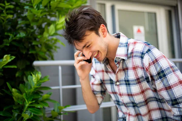 側の肖像画の幸せな若い男と話して携帯電話外 — ストック写真