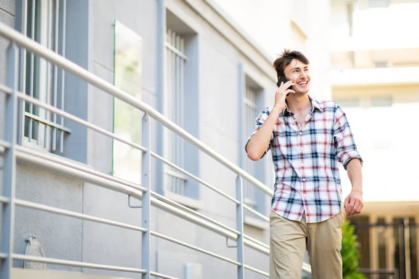 幸せな若い男の肖像屋外で携帯電話と歩くと話す — ストック写真