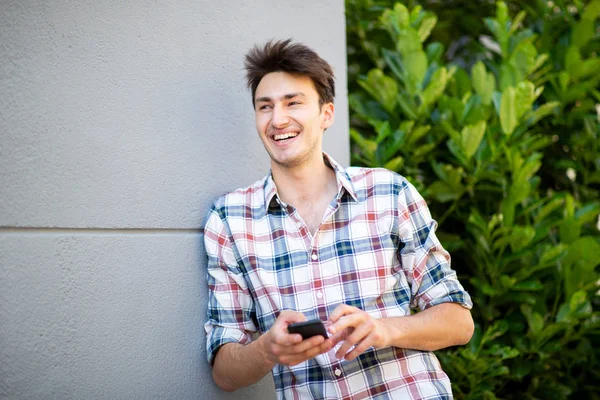 Ritratto Giovane Uomo Sorridente Appoggiato Muro Con Cellulare Mano — Foto Stock