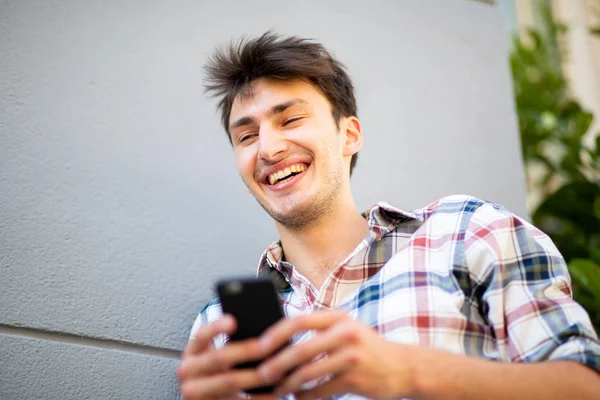 拍下年轻人笑着拿着手机的近照 — 图库照片