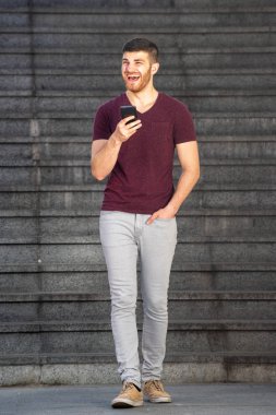 Cep telefonuyla yürüyen bir gencin vücut portresi.