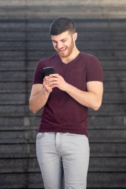 Cep telefonuna bakıp gülen genç bir adamın portresi.