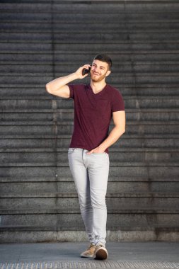 Genç bir adamın cep telefonuyla yürüme ve konuşma portresi.