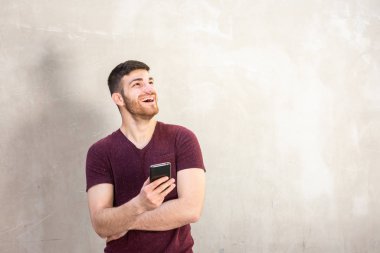 Elinde cep telefonu olan gülümseyen genç adamın portresi.