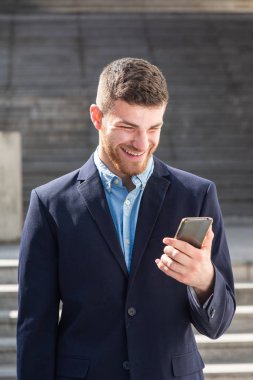 Şehirde cep telefonuna bakan gülümseyen iş adamının portresi