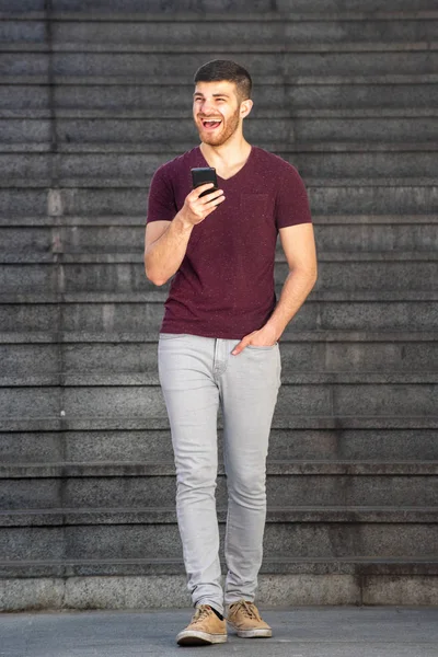 Cep telefonuyla yürüyen bir gencin vücut portresi.