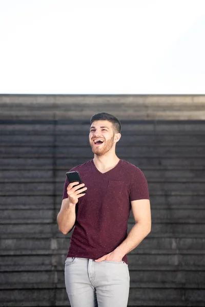 携帯電話で笑う若い男の肖像画 — ストック写真
