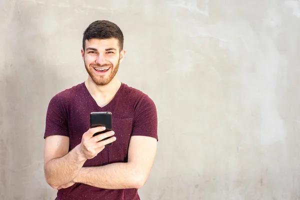 Portret Lachende Jongeman Met Baard Die Mobiele Telefoon Tegen Muur — Stockfoto
