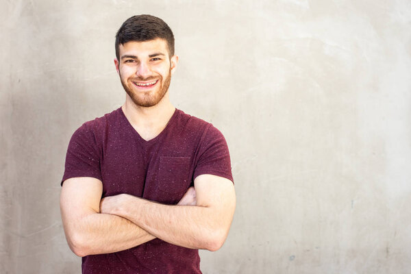 Portrait cool happy guy with beard posing with arms crossed 