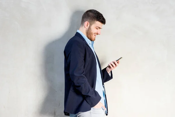 携帯電話を見ている若いビジネスマンのサイドポートレート — ストック写真