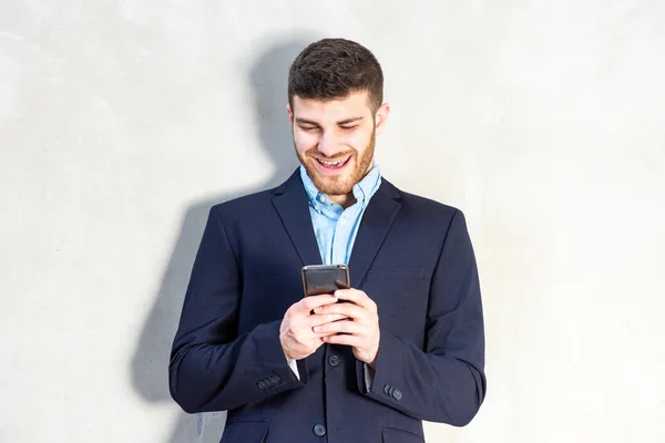 Porträt Eines Lächelnden Jungen Geschäftsmannes Der Auf Sein Handy Blickt — Stockfoto