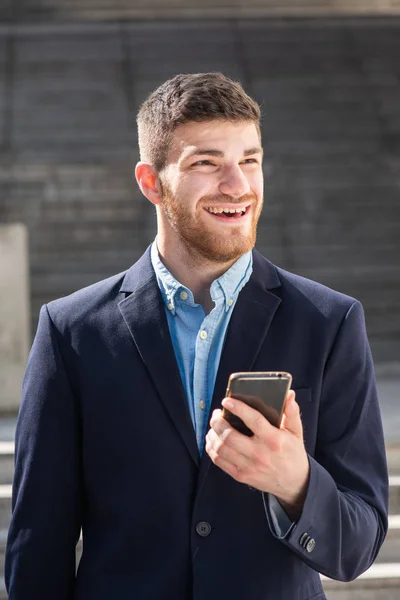 Retrato Joven Empresario Sonriente Sosteniendo Teléfono Móvil Mirando Hacia Otro — Foto de Stock