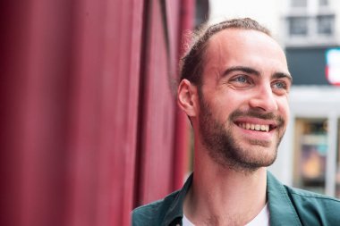 Şehrin dışında sakallı, gülümseyen bir adamın portresi.