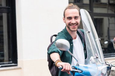 Şehirde motosikletli mutlu bir gencin portresi. 