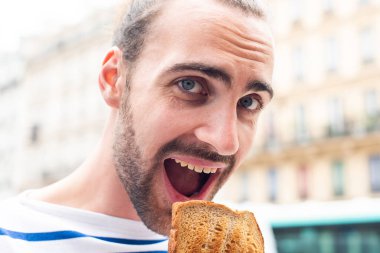 Kentin dışında sandviç yiyen genç adamın portresini kapat.