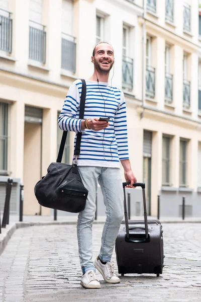 全身ポートレートの幸せな旅行男歩くでスーツケースバッグと携帯電話で街の通り — ストック写真