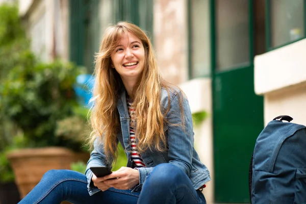 Portret Lachende Jonge Vrouw Zitten Buiten Met Mobiele Telefoon — Stockfoto