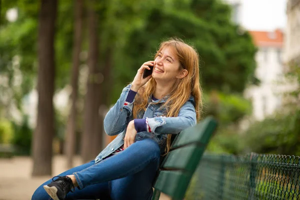 Sidoporträtt Leende Ung Kvinna Som Sitter Parkbänk Och Pratar Med — Stockfoto