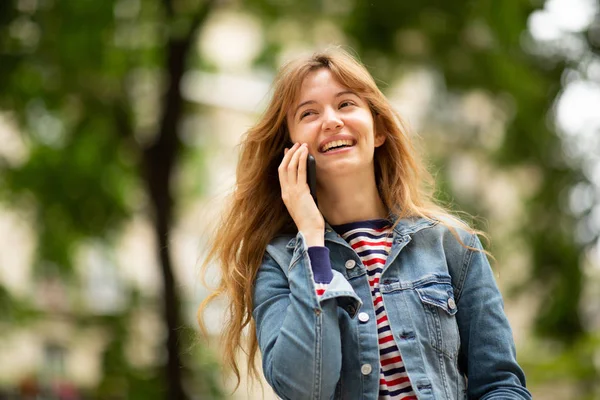 公園で携帯電話と話して笑顔の若い女性の肖像画を閉じます — ストック写真