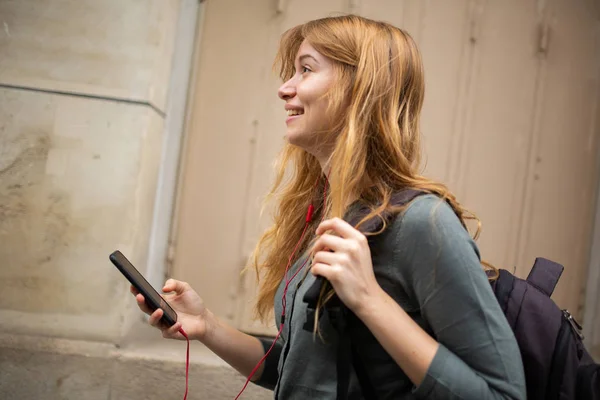 Kulaklık Cep Telefonuyla Müzik Dinleyen Gülümseyen Genç Bir Kadının Yan — Stok fotoğraf