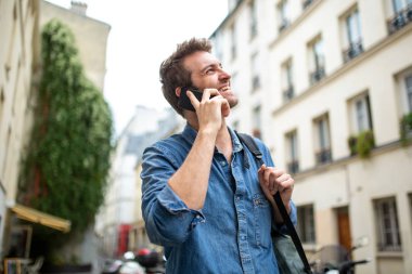 Kapalı portre mutlu adam cep telefonuyla konuşuyor ve başka yere bakıyor.