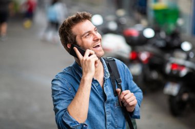 Şehirde cep telefonuyla konuşan ve gülen yaşlı adamın portresi.