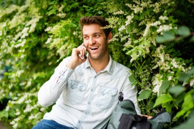 Parktaki bankta oturmuş cep telefonuyla konuşan mutlu bir adamın portresi.