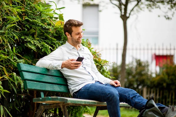幸せな男の肖像 携帯電話で公園のベンチに座って — ストック写真
