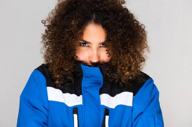 Kışlık ceketli, ciddi bir Afro-Amerikan kadının ön portresini yakın çekin.