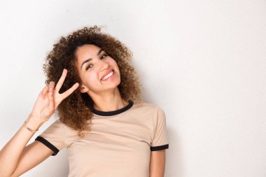 Mutlu gülümseyen genç bir kadının portresi. Beyaz duvarda barış işareti var.