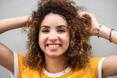 Kıvırcık saçlı, mutlu genç bir kadının portresini yakından çek.