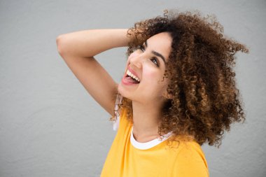 Kıvırcık saçlarıyla gülümseyen ve yukarı bakan güzel Afro-Amerikan kadının yan portresi.