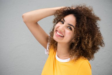 Kıvırcık saçlı, gülümseyen, güzel, Afro-Amerikan bir kadının yan portresi. 