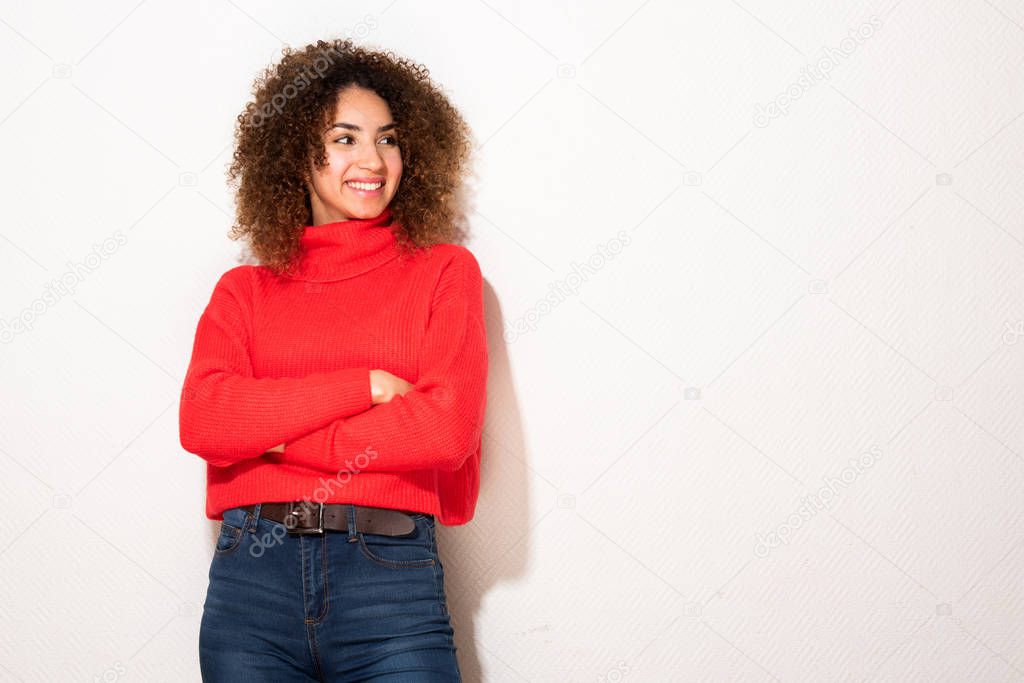 Portrait happy young african american woman in red sweater with arms crossed by white background 