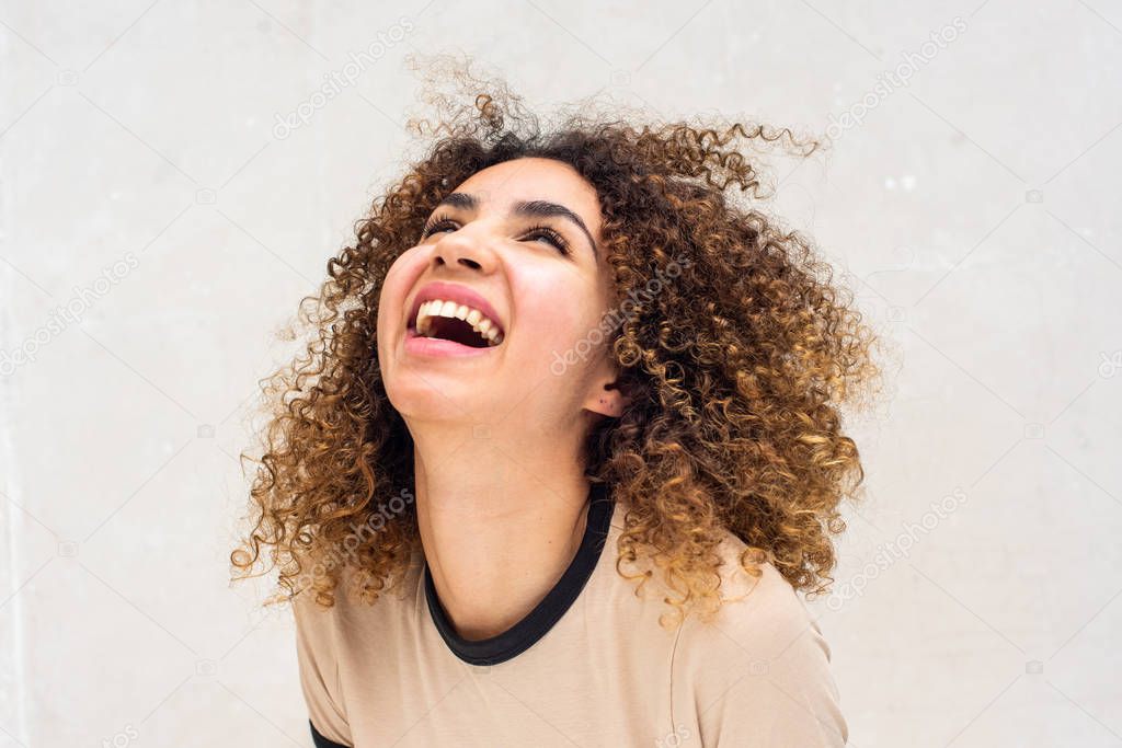 Close up portrait of young african american woman with curly hair laughing against white background